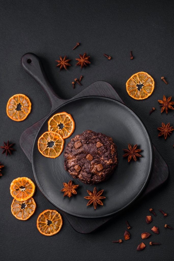 Delicious fresh oatmeal round cookies with chocolate on a black ceramic plate