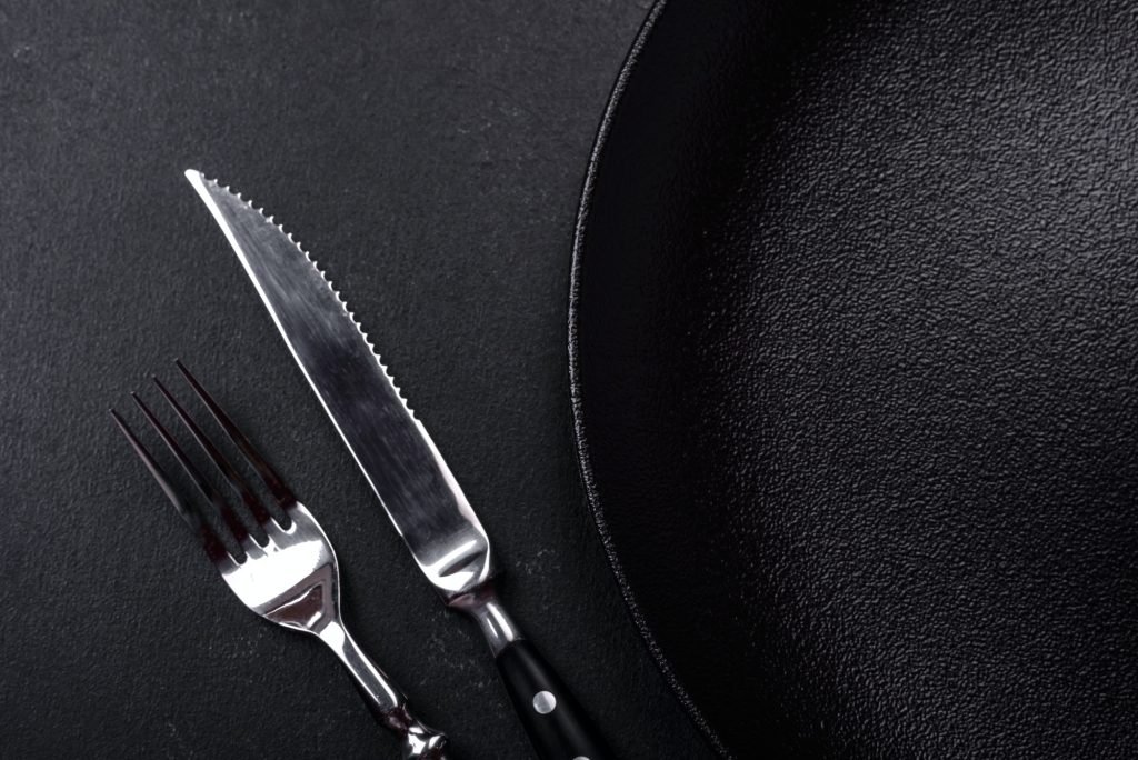 Empty beautiful black ceramic plate on a dark concrete background