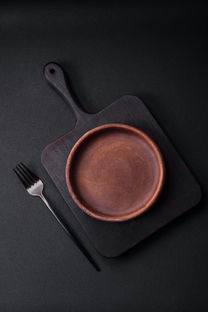 Empty brown colored ceramic plate on dark concrete background